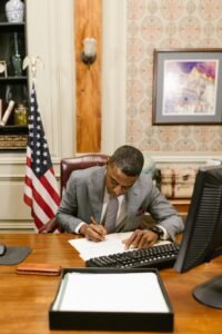 African American lawyer writing documents at a desk in a formal law office.